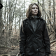 Maggie walks stupefied through a sparse forest.